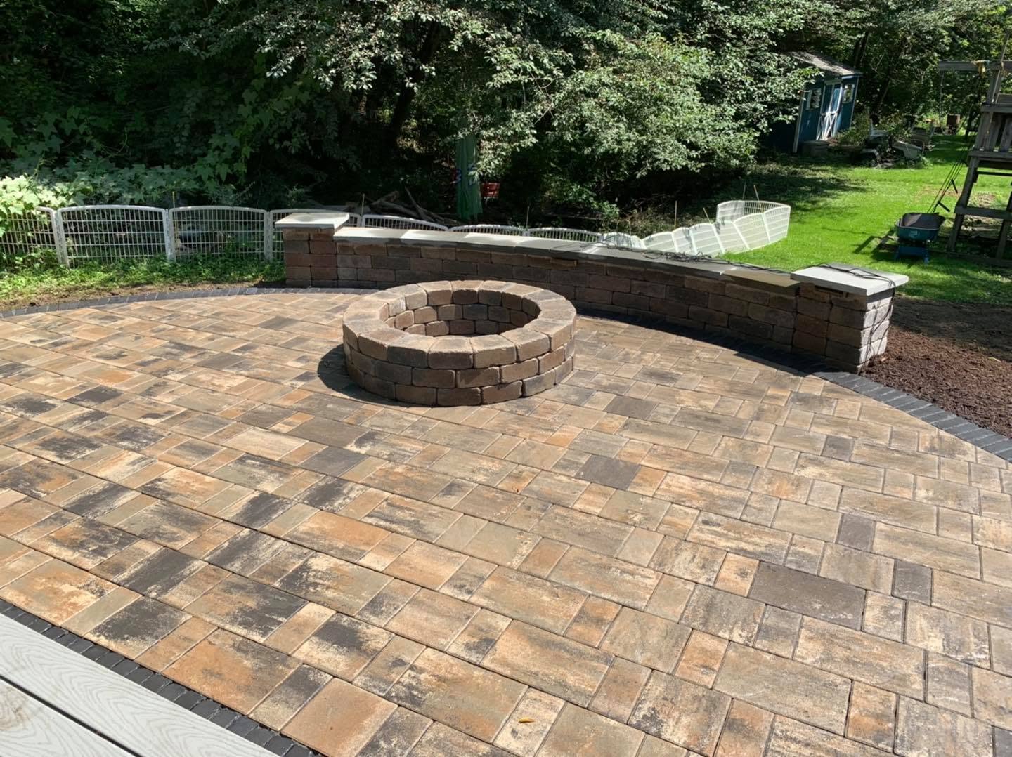 Paver patio with a stone fire pit and sitting wall