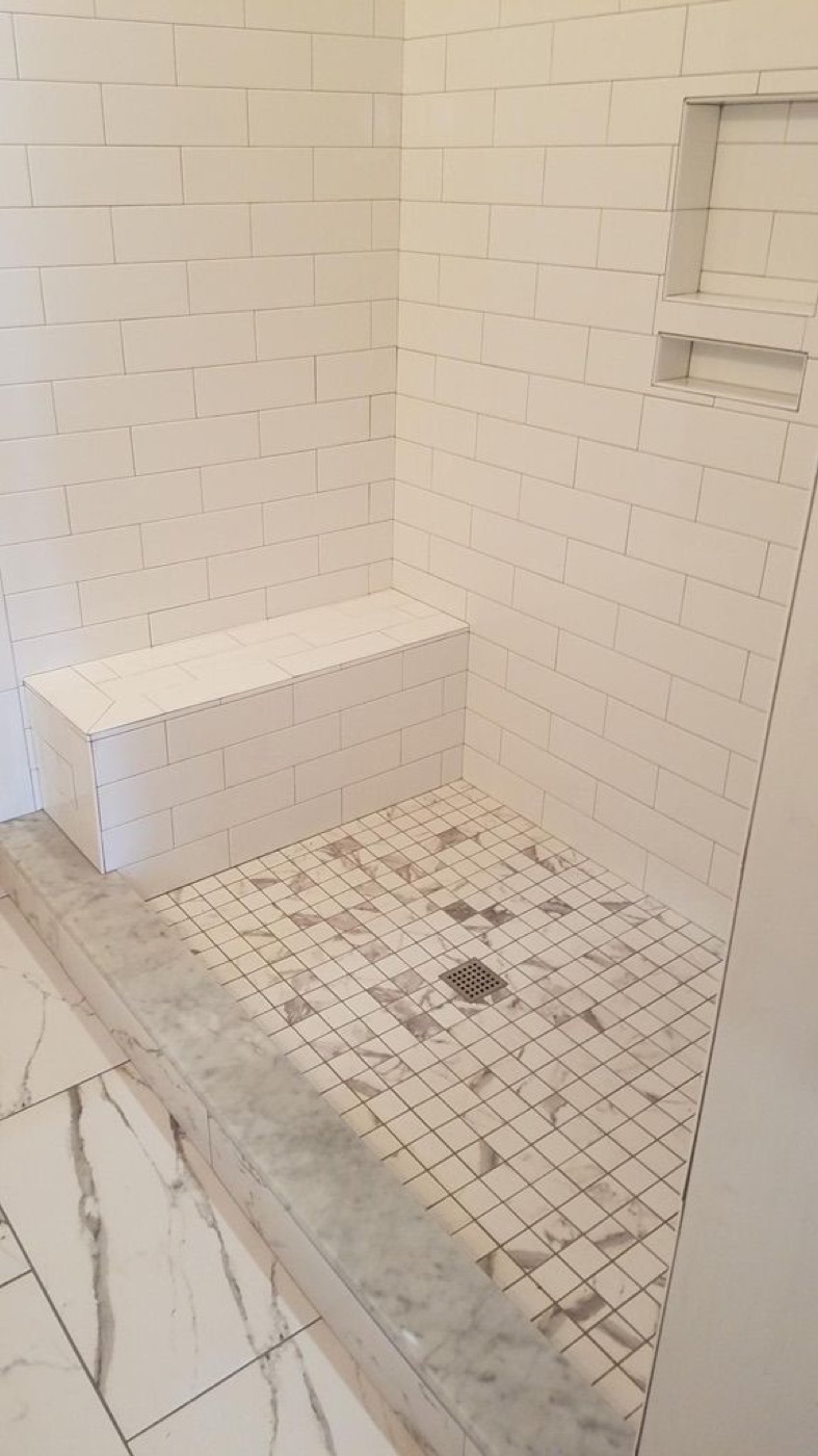 Custom walk-in shower tiled in white subway tile with a built-in bench and mosaic floor