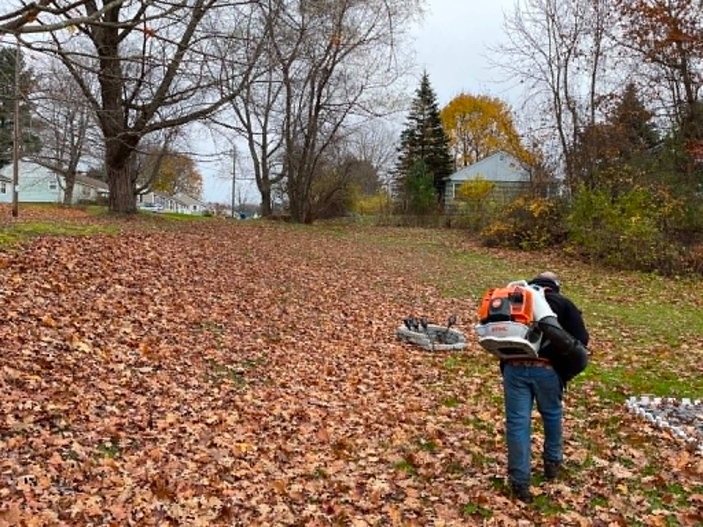 Crew member clearing leaves with a backpack blower