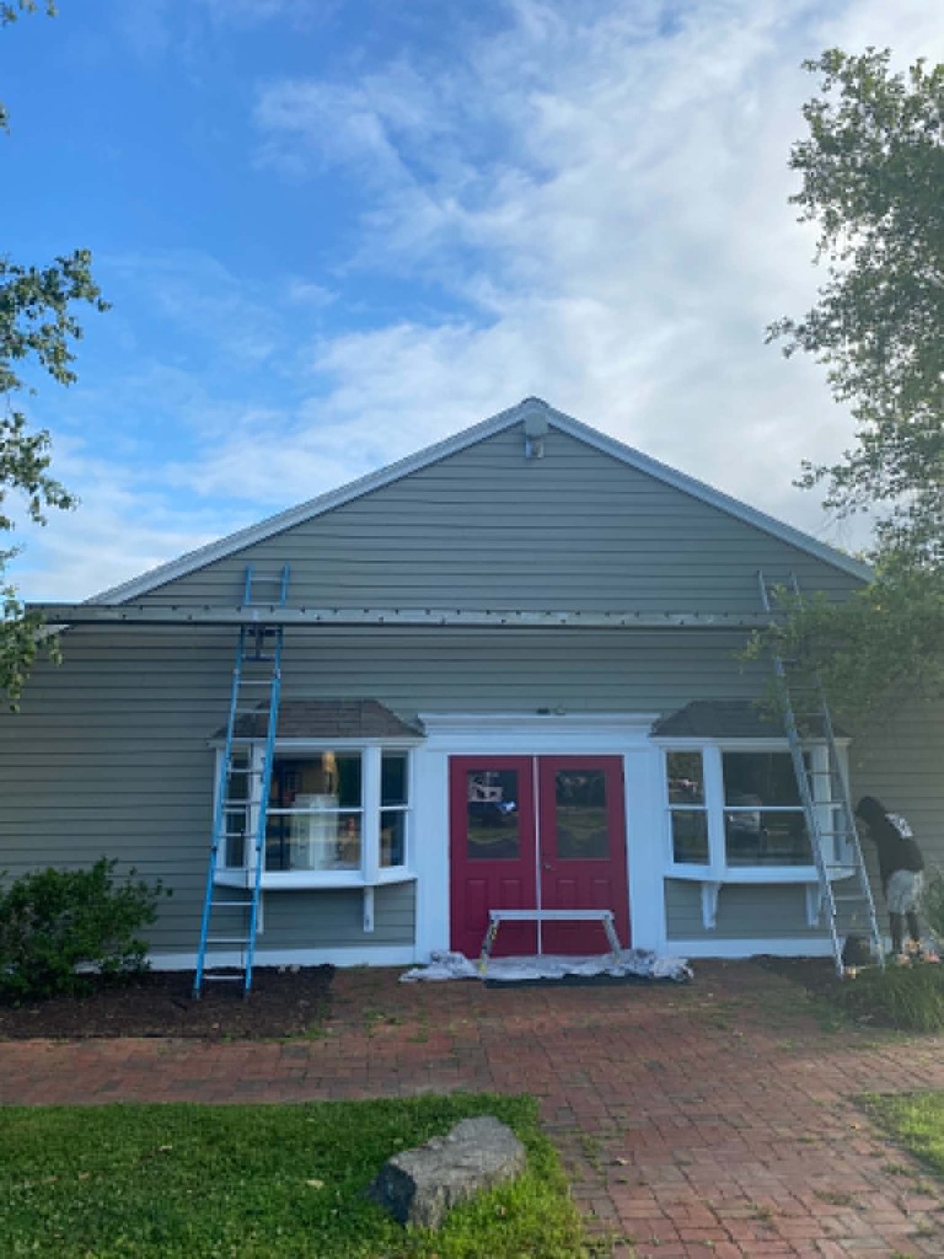 The same storefront finished with fresh green siding, white trim, and red double doors