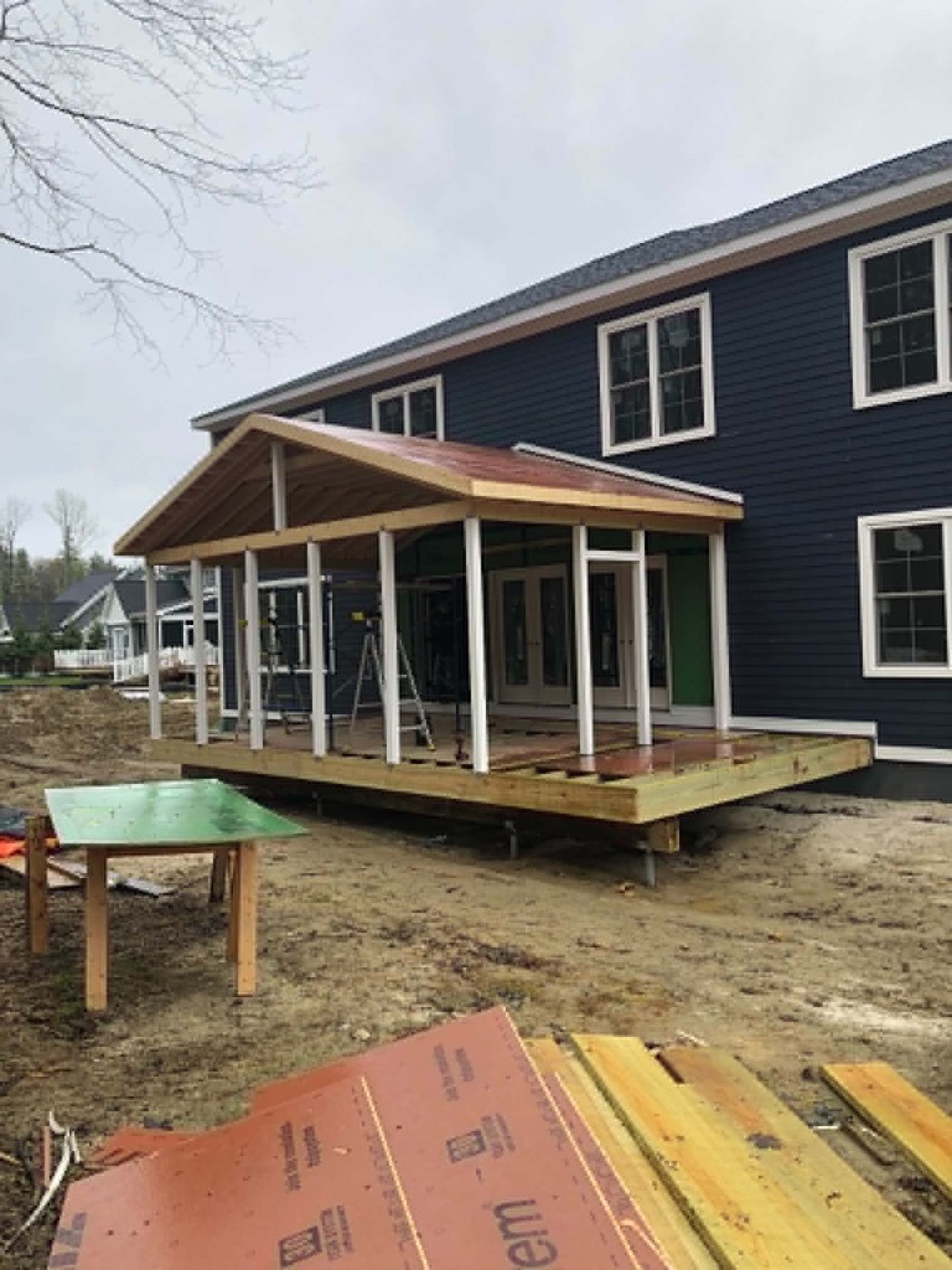 Finished covered farmer&rsquo;s porch with a gable roof on a navy clapboard home