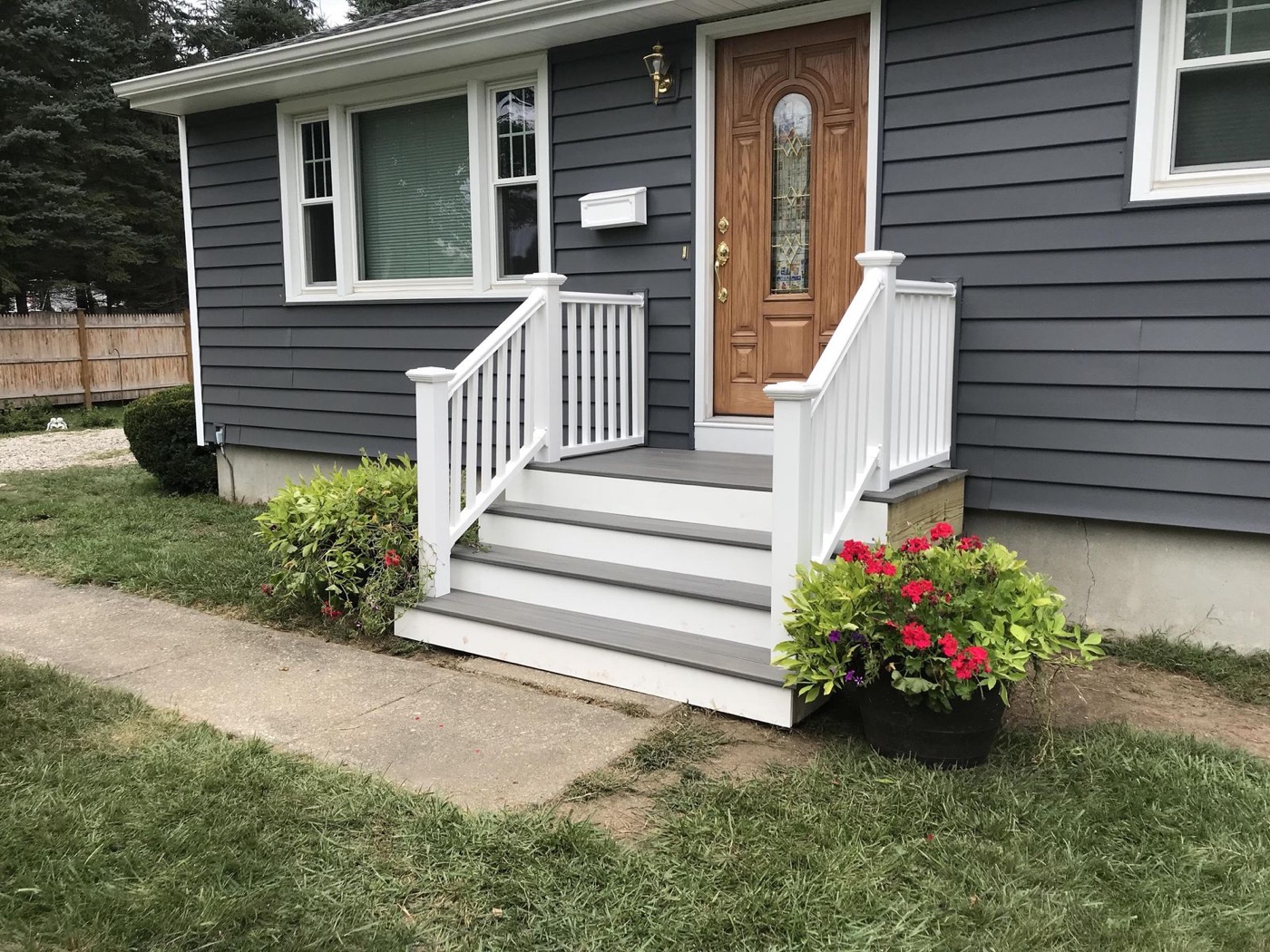 Freshly built white porch and steps on a navy home with a red front door
