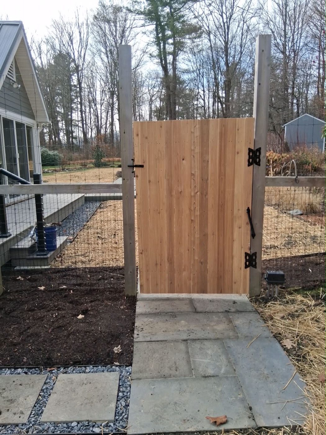 New cedar garden gate and wire fence beside a bluestone stepping-stone path