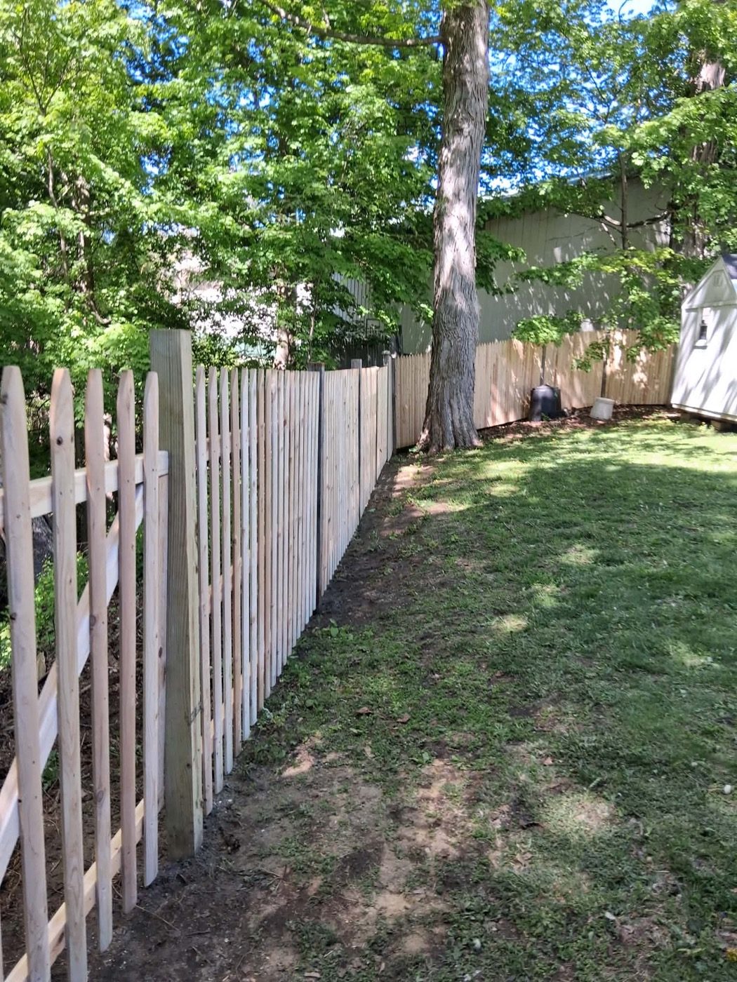 New spaced-picket wooden fence line between two backyards