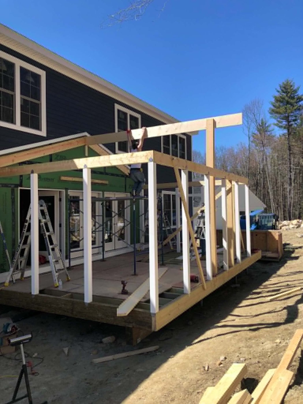 Crew framing the porch roof under a clear blue sky
