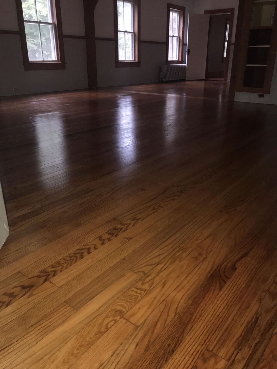 Rich hardwood floor finished to a mirror shine in a sunlit room