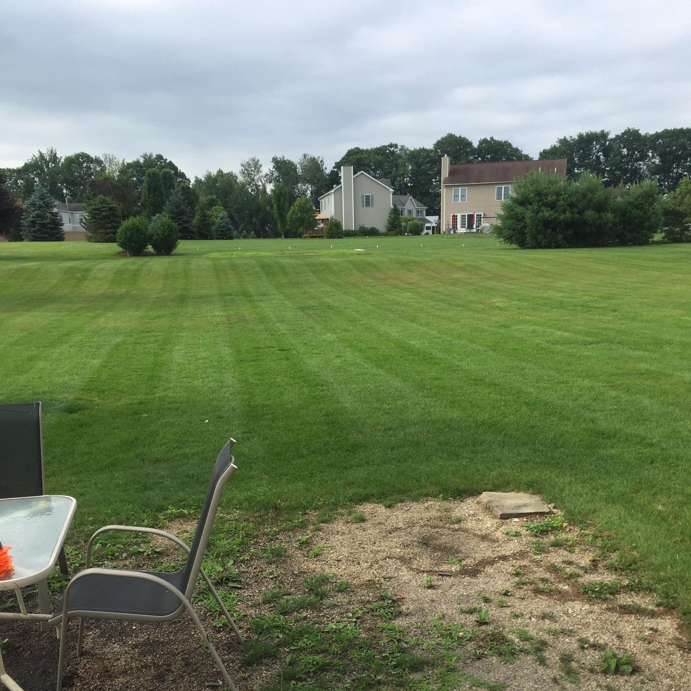 Wide freshly mowed lawn sweeping up to a two-story home